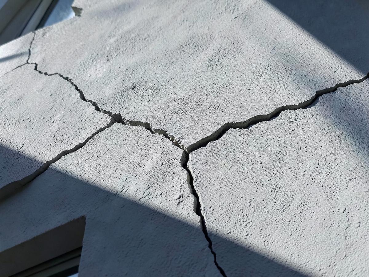 Fissure structurelle traversant l'enduit d'une façade